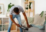 man-vacuuming-couch-front-view_23-2149482275