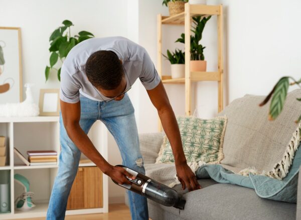 man-vacuuming-couch-front-view_23-2149482275